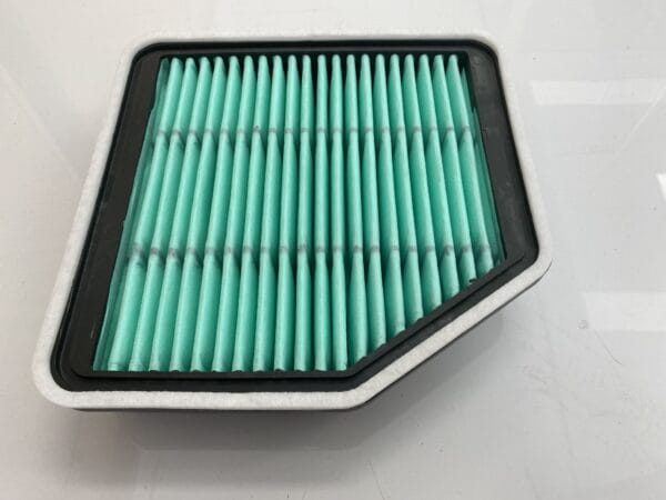 A rectangular air filter with a green pleated surface and a black border, placed on a white background.